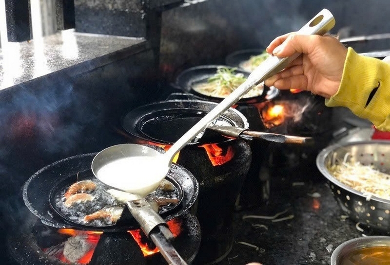 Close-up of jumping shrimp pancakes sizzling on a cast-iron pan