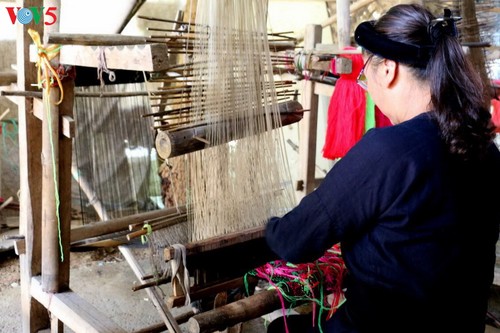 Cham artisan weaving traditional fabric on a loom.