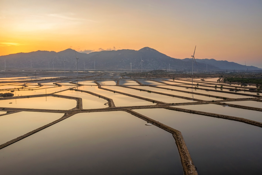 Wide-angle sunrise view of Ca Na salt fields with mirror reflections