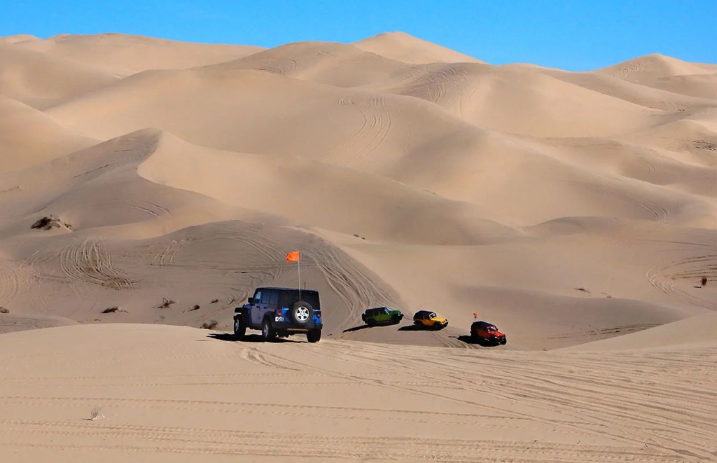 Jeep driving across sand dunes
